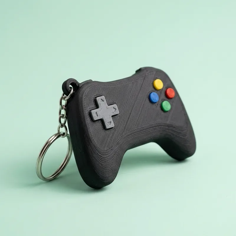 Llavero de control de videojuego negro con botones de colores y cruceta gris