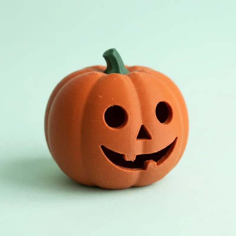 Calabaza naranja impresa en 3D con ojos redondos y una sonrisa tallada, tallo verde