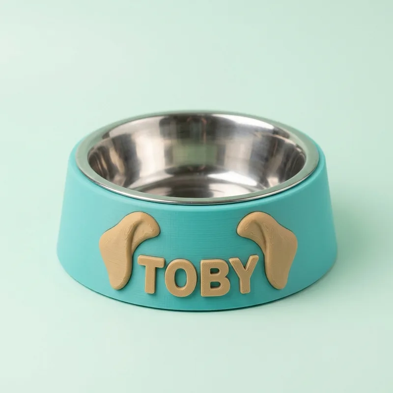 Comedero turquesa con orejitas de beagle y el nombre Toby, con un plato de acero encajado